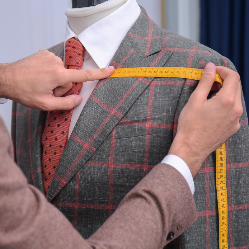 fashion grid 3 a tailor measures the shoulder of a men's suit jacket